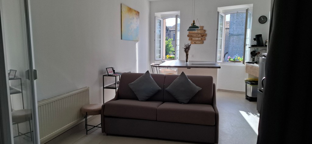 Salle de séjour située au rez-de-chaussée avec petit canapé, espace de travail et ambiance moderne.